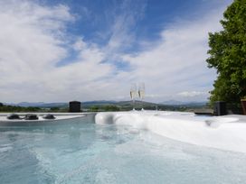 A hot tub with champagne glasses overlooking a landscape at Nethermill Lodges in Port Glasgow