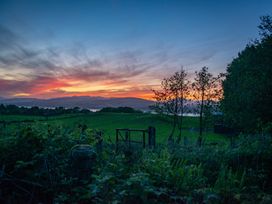 A sunset over a field with mountains and trees at Nethermill Lodges in Port Glasgow