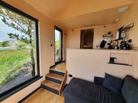 A living room with a sofa and kitchen counter at Cullinview in Isle of Skye