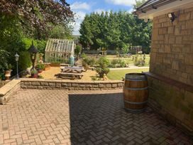 A garden with a greenhouse and a barrel at Fenton Drive in Wooler