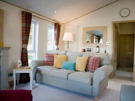 A living room with a sofa, lamp, and mirror at Orchid 9 in Christchurch