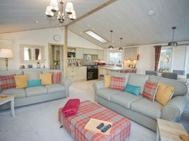 A living room with sofas and a kitchen at Orchid 9 in Christchurch