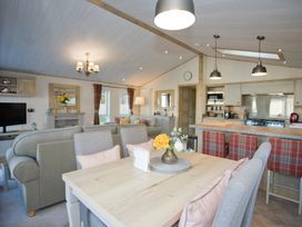 A living room with a sofa and kitchen area at Orchid 9 Christchurch