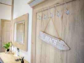 A hallway with coat hooks and wooden sign at Orchid 9 Christchurch