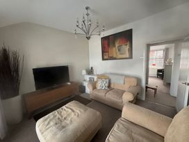 A living room with a sofa, armchair, television and chandelier at Penmaenmawr Coastal Retreat