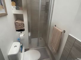 A bathroom with a shower, toilet, and towels at Penmaenmawr Coastal Retreat