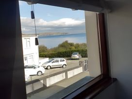 A view through a window showing a landscape with sea and cars at Penmaenmawr Coastal Retreat