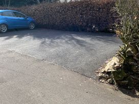 An outdoor parking area with a blue car and a hedge at The Haven in Penrith