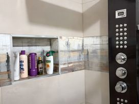 A shower with various bottles on a shelf at Cherry Chirp Cottage Enniskillen