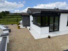 An outdoor area with a house, gravel driveway, and planters at Cherry Chirp Cottage in Enniskillen