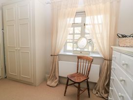 A bedroom with a wardrobe, chair and window at Foxhill Farm Barn Cheltenham