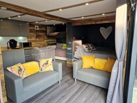 A living room with a sofa and kitchen area at Birdsong lodge near Hawthorn Farm near Sutton-On-Sea