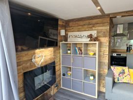 A living room with a television, bookshelf, and sofa at Birdsong lodge near Hawthorn Farm near Sutton-On-Sea