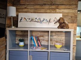 A living room with a shelf holding books and a lamp at Birdsong lodge near Hawthorn Farm near Sutton-On-Sea