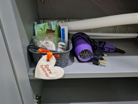 A toiletries basket and hair dryer in a bathroom at Birdsong lodge near Hawthorn Farm in Sutton-On-Sea