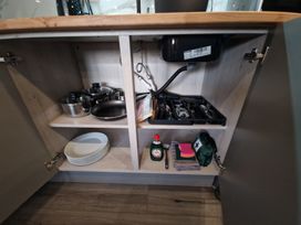 A kitchen cabinet with pots, plates, and utensils at Birdsong lodge near Hawthorn Farm