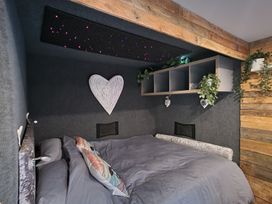 A bedroom with a bed and shelf at Birdsong lodge near Sutton-On-Sea