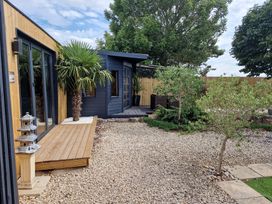 A garden with a wooden deck and outdoor shed at Birdsong lodge Hawthorn Farm near Sutton-On-Sea
