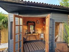 An outdoor room with a wooden table and mirror at Birdsong lodge near Hawthorn Farm
