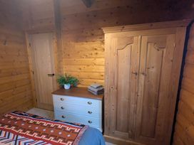 A bedroom with a wooden wardrobe and dresser at Pineshadow Lodge in Louth
