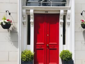 A red door with decorative elements and hanging planters at Fountain Hill House Londonderry