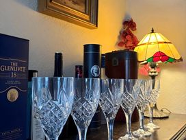 A display of whiskey bottles and crystal glasses with a lamp at Fountain Hill House in Londonderry