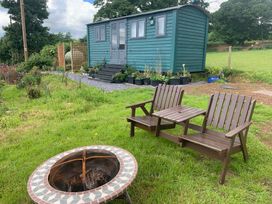 An outdoor area with a shepherd's hut and chairs at Bluebell Shepherd’s Hut in Llanfairpwllgwyngyll