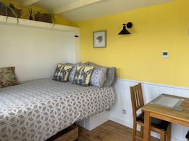 A bedroom with a bed and table in Bluebell Shepherd’s Hut in Llanfairpwllgwyngyll