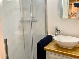 A bathroom with a shower and sink at Bluebell Shepherd’s Hut in Llanfairpwllgwyngyll