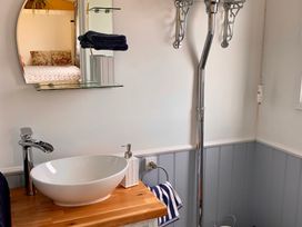 A bathroom with a sink and mirror at Bluebell Shepherd’s Hut in Llanfairpwllgwyngyll