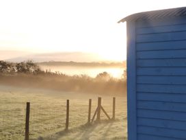 A blue shed with a fence and mist in a field at Bluebell Shepherd’s Hut in Llanfairpwllgwyngyll