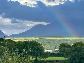 A view showing mountains, rainbow, and greenery at Bluebell Shepherd’s Hut in Llanfairpwllgwyngyll