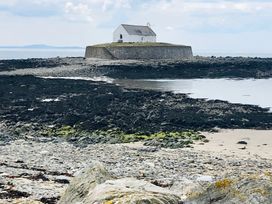 A coastal view featuring a building on a rocky shore near the ocean at Bluebell Shepherd’s Hut in Llanfairpwllgwyngyll