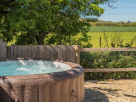 A hot tub with a wooden fence and greenery at Cotswold Nights in Ashton Under Hill