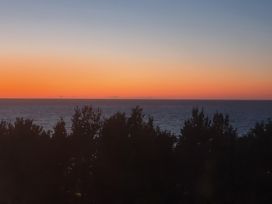 An ocean view with trees during sunset at Sea view cottage in Penmaenmawr
