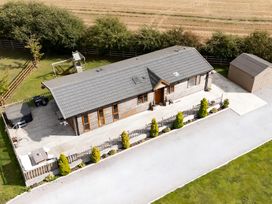 An outdoor view of a house with a deck and garden at Hedgehog Lodge in York