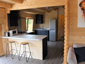 A kitchen with a sink, refrigerator, and stools at Cotswold Nights Away in Evesham