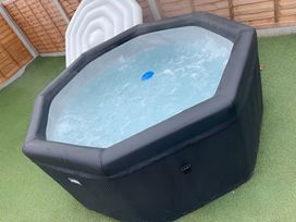 A hot tub filled with water in a garden at Cotswold Nights Away in Evesham