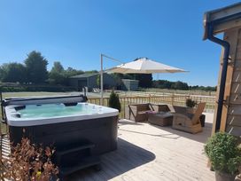 A patio area with a hot tub and outdoor furniture at Fox Lodge in York