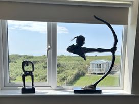 Two sculptures on a windowsill with a view of a garden at Country Retreat Sleeps 2 in Holyhead