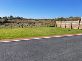 A grassy area with a fence and road at Country Retreat Sleeps 2 Holyhead