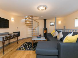 A living room with a spiral staircase and a fireplace at The Old Well House in Redruth