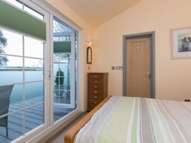 A bedroom with a bed and a window leading to a balcony at The Old Well House in Redruth