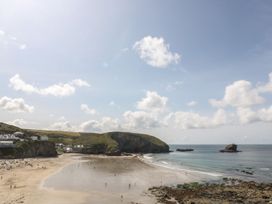 A beach with people walking and houses on a hill at The Old Well House in Redruth