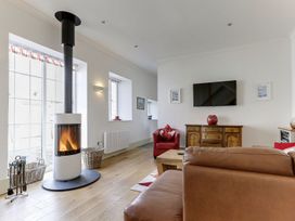 A living room with a wood stove and sofa at Poppyfields Stable in Redruth