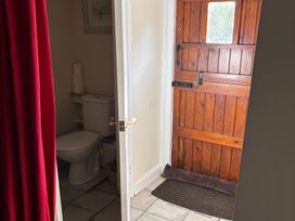 A bathroom with a toilet and a wooden door at 2 Bed Barn in Barroway Drove near Downham Market