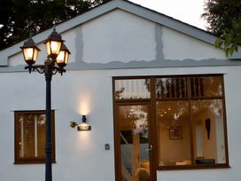 A cottage exterior with a lamp post and windows at Honey Bee Cottage in Welshpool