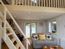 A living room with a staircase and kitchenette at Honey Bee Cottage in Welshpool