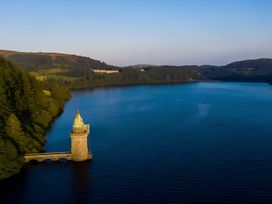 A lake with a tower and forest surrounding it at Honey Bee Cottage Welshpool
