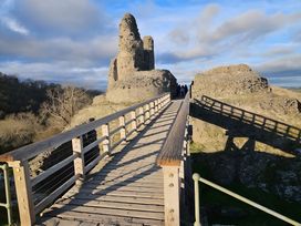 A bridge leading to castle ruins with people at Honey Bee Cottage in Welshpool
